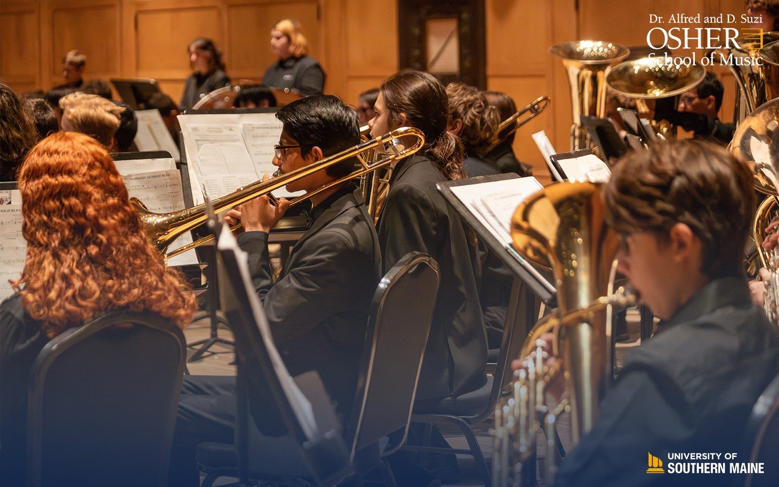 a group of student musicians with a male appearing trombone player in the center with black hair and glasses. In the upper right of the image is the Dr. Alfred and D. Suzi Osher School of Music logo, and the bottom right is the University of Southern Maine logo.