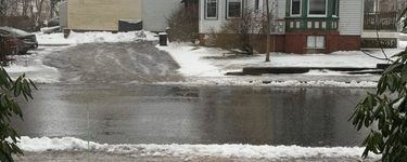 Snowy Sidewalk and street with a house across the st