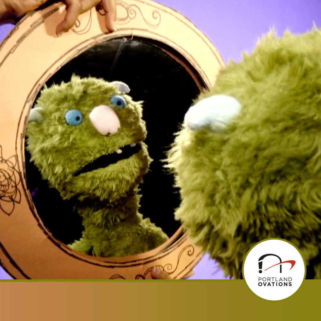 FY26_Ovations_portTIX_1080X1080_Leonardo a puppet of a green monster looks at himself in a round mirror. the portland ovations logo is in the bottom right of the image.